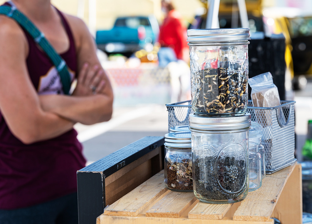 Person standing at a market vendor stand with their arms crossed