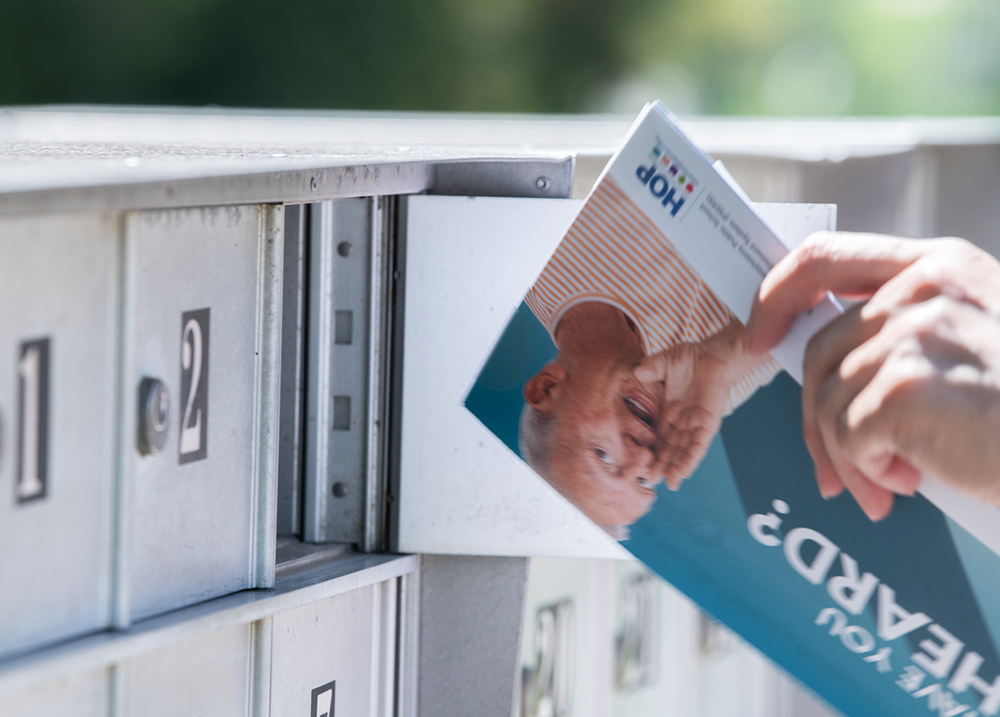 Hand grabbing a mailer out of a mailbox that says Have You Heard?