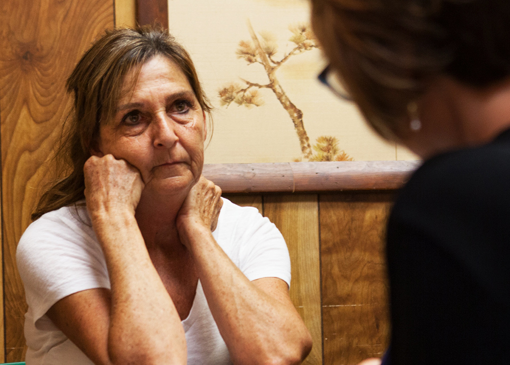 Two people have a conversation, the woman in focus has a questioning look as she listens