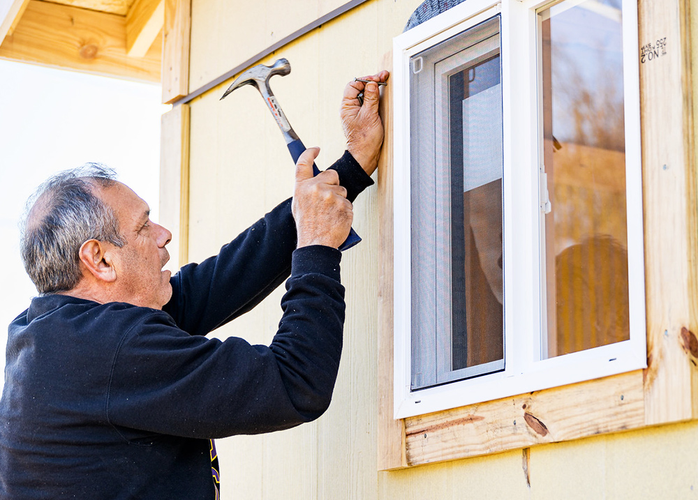 Man hammering a nail into trim by a new winder