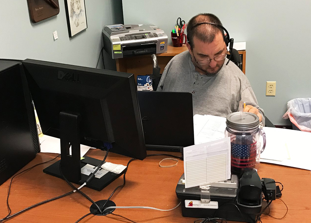 Man working behind two monitor screens