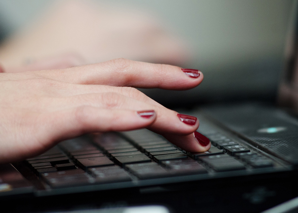 Close-up of a hand typing on a laptop keyboard