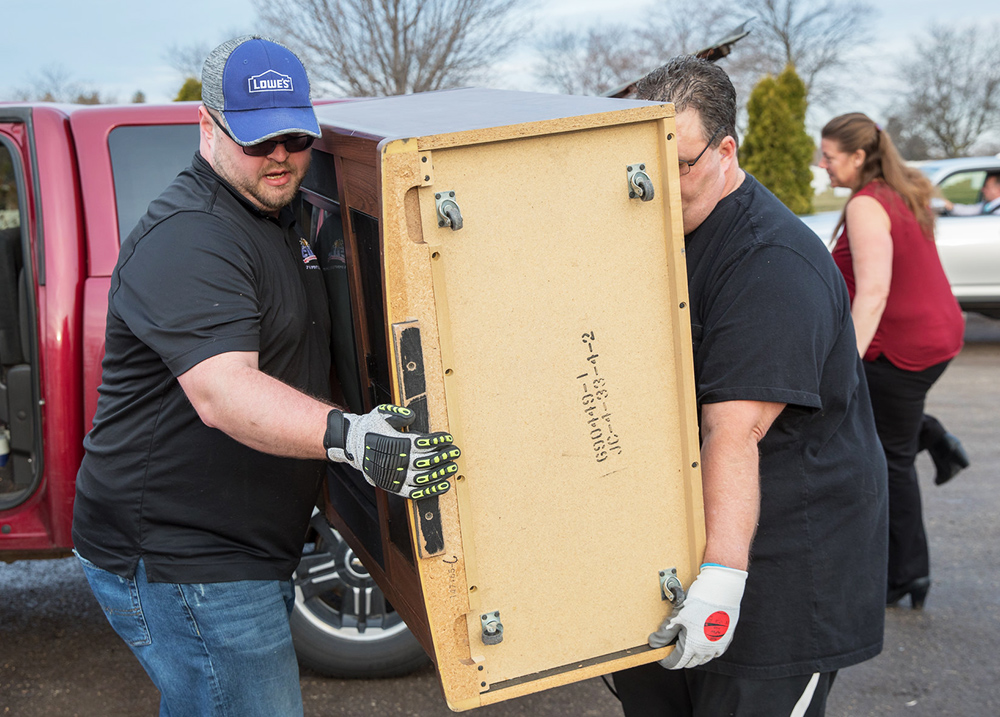 Two people moving a large piece of furniture