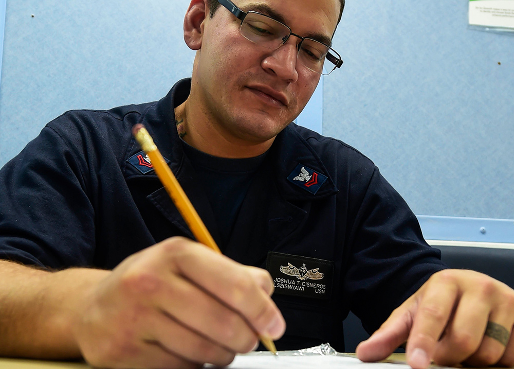 Person writing on paper with a pencil