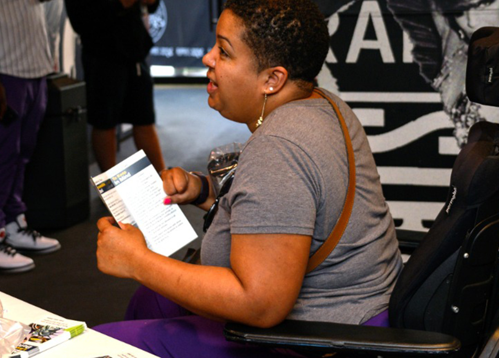 Woman who uses a wheelchair holds a pamphlet