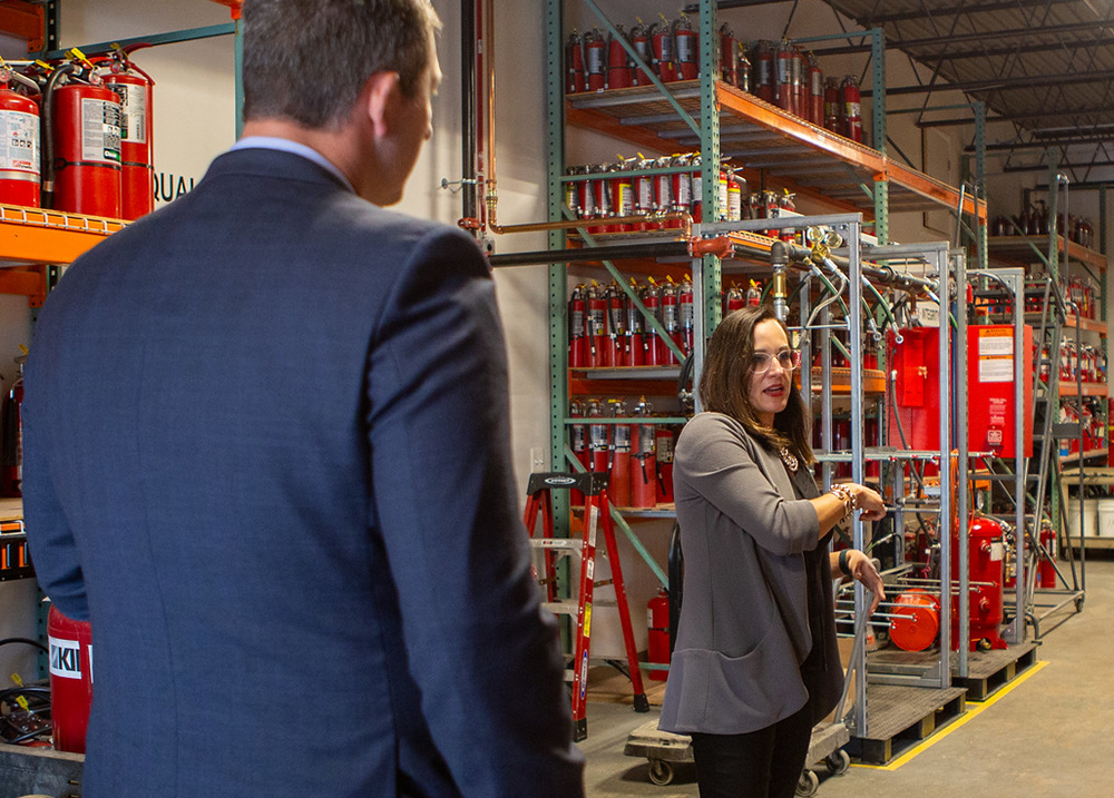 Two people walking through a business that makes fire extinguishers