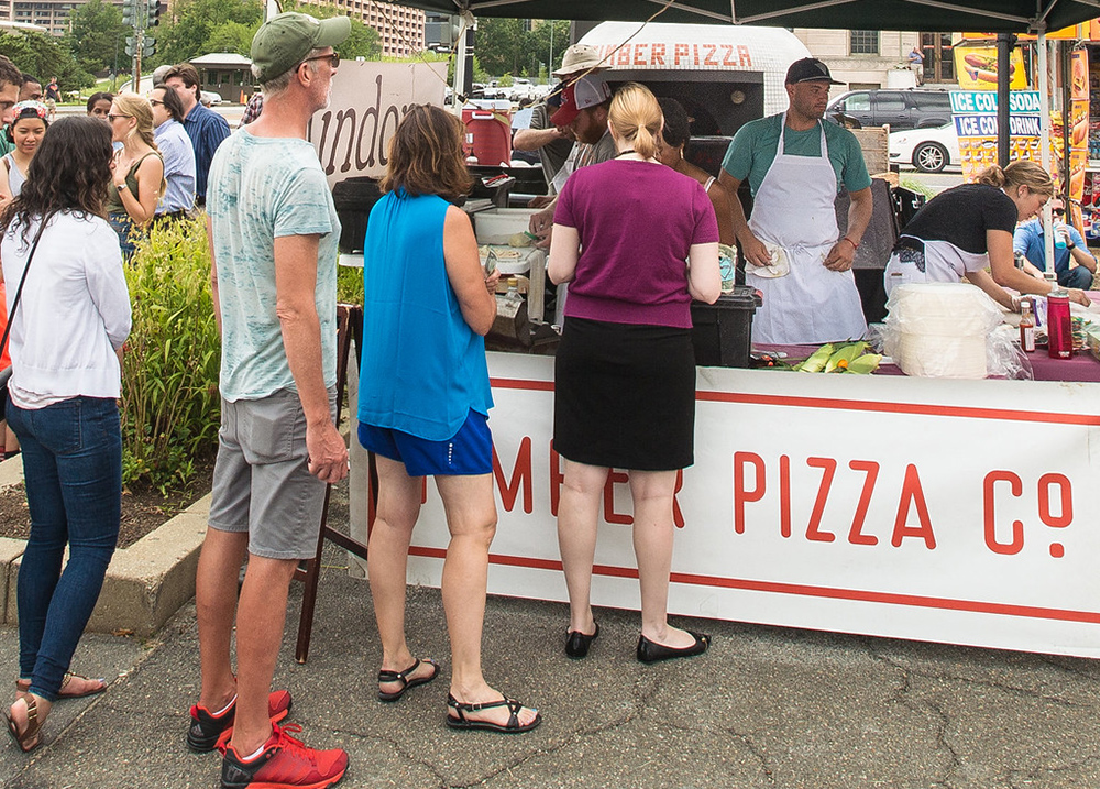 People standing in line for pizza at an outdoor market