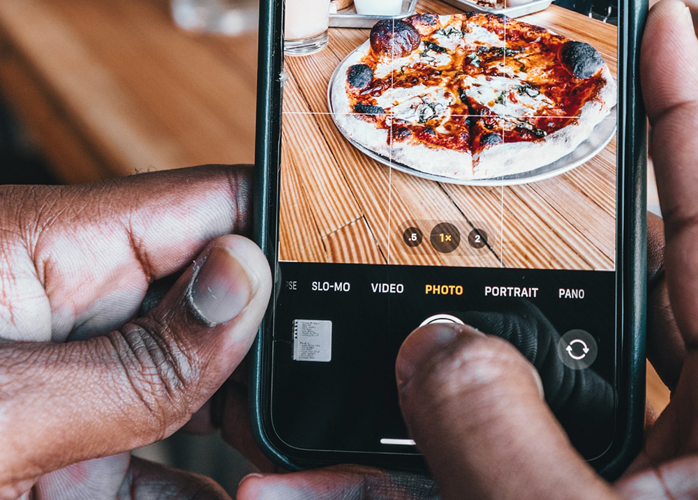 Person taking a photo of a pizza with their phone