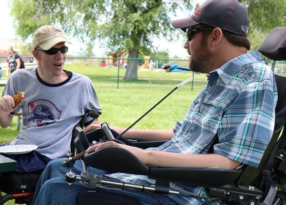 Two wheelchair users talk in a park