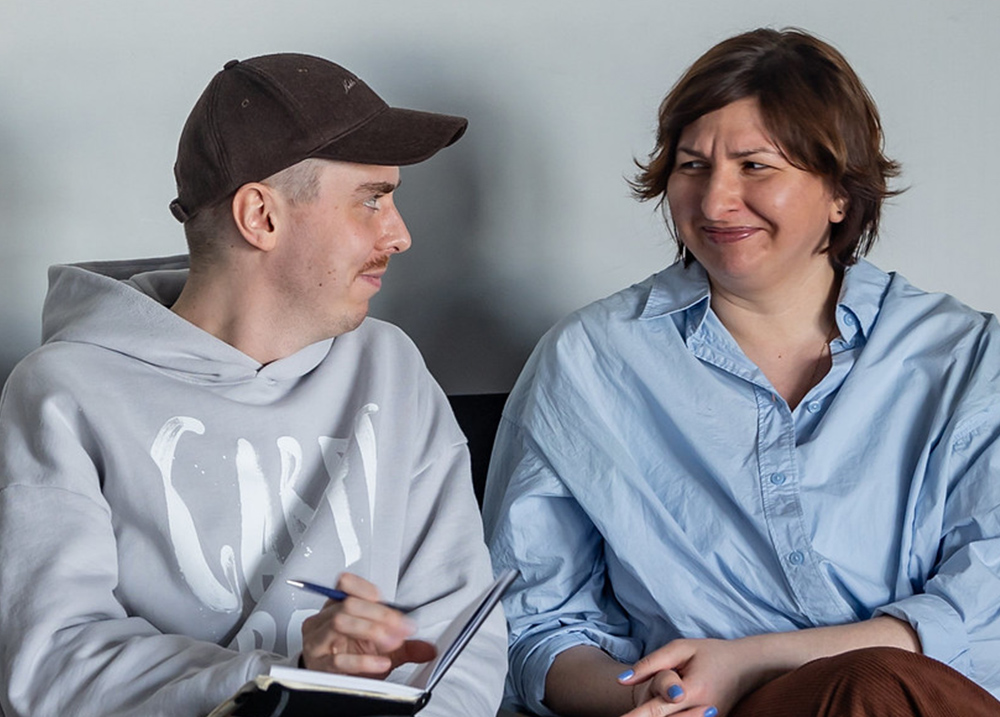 Two people sitting next to each other looking at each other