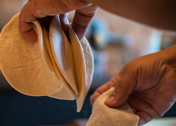 Close-up of hands holding small, round pizza crusts