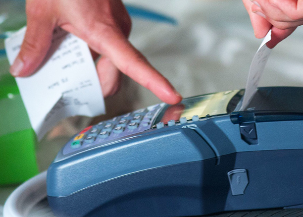 Close-up of hands pulling a receipt out of a payment terminal