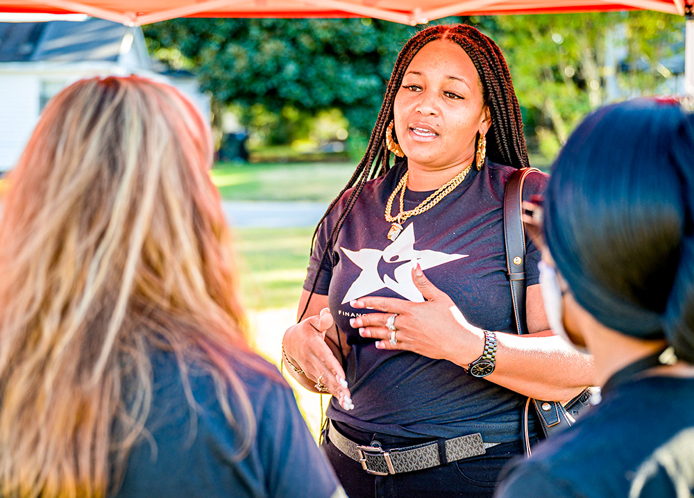 Woman at an outdoor event talking to two other people