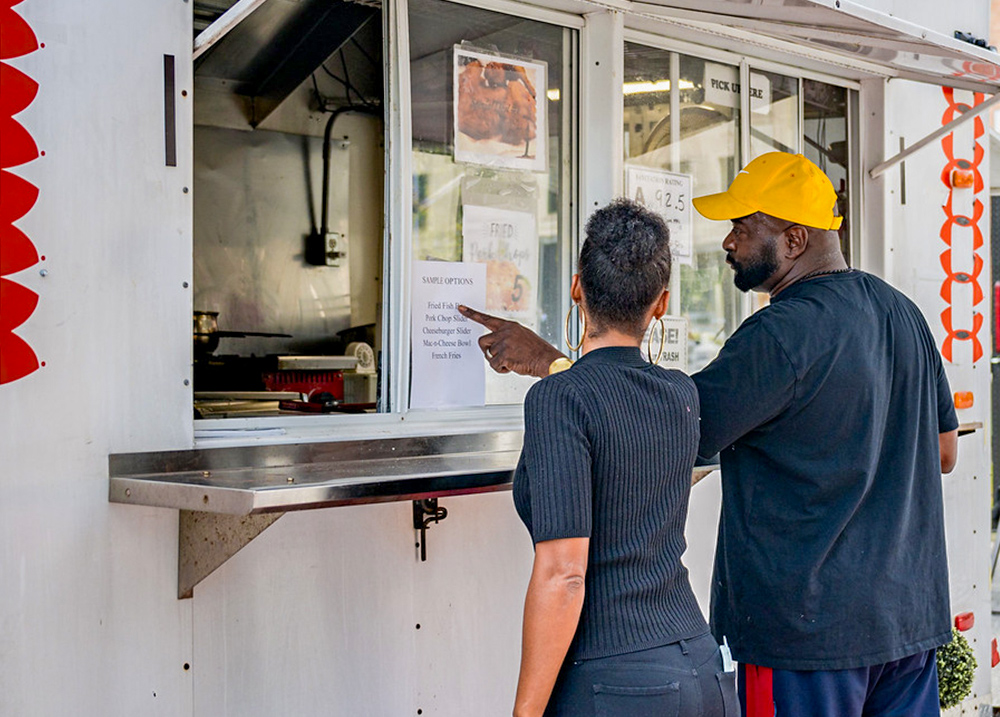 Two people ordering from a food truck
