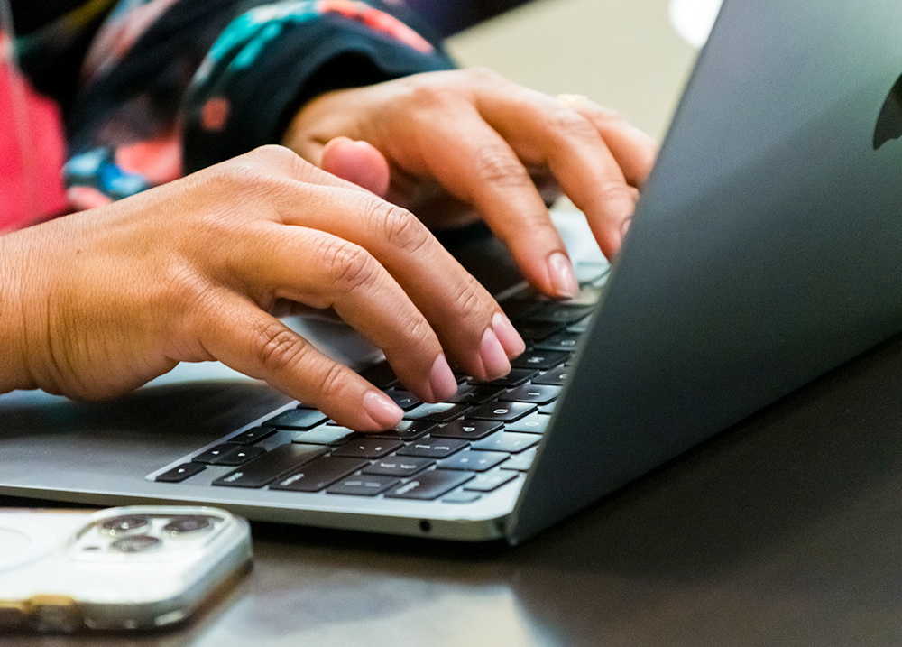 Hands typing on a laptop keyboard