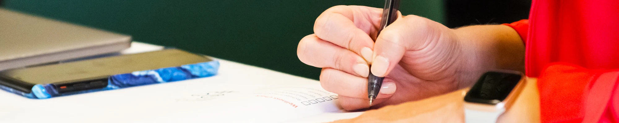 Close up of a hand holding a pen writing in a notebook