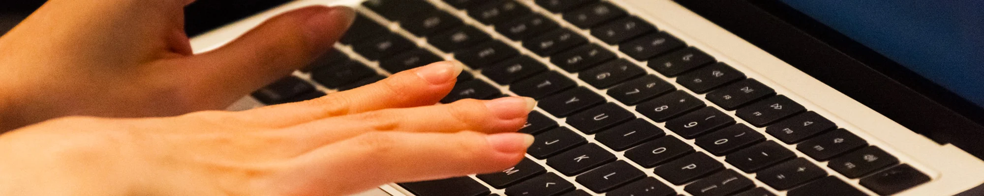 Close up of fingers typing on a laptop keyboard