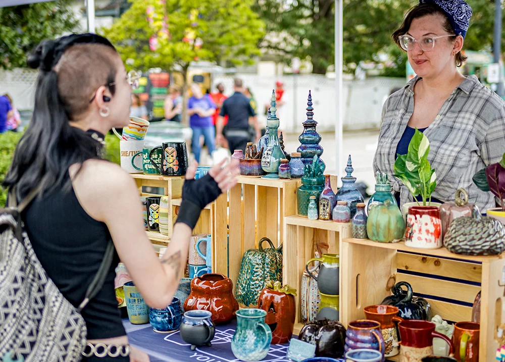 Vendor talking to a customer at a stand that sells pottery