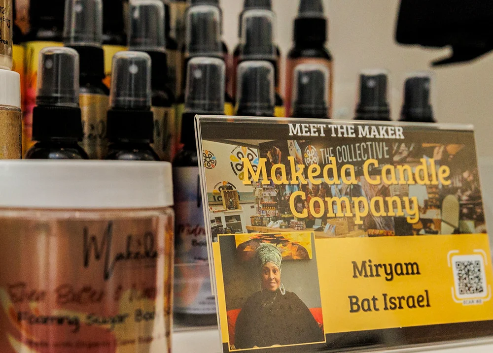 Spray bottles with a sign in front of them that says Meet the Maker: Makeda Candle Company