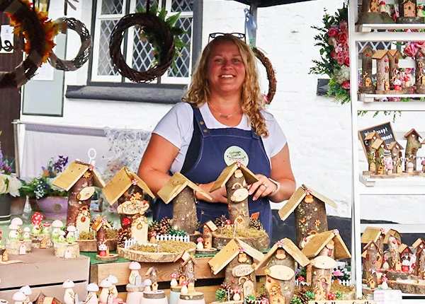 Woman selling handmade fairy houses at a market