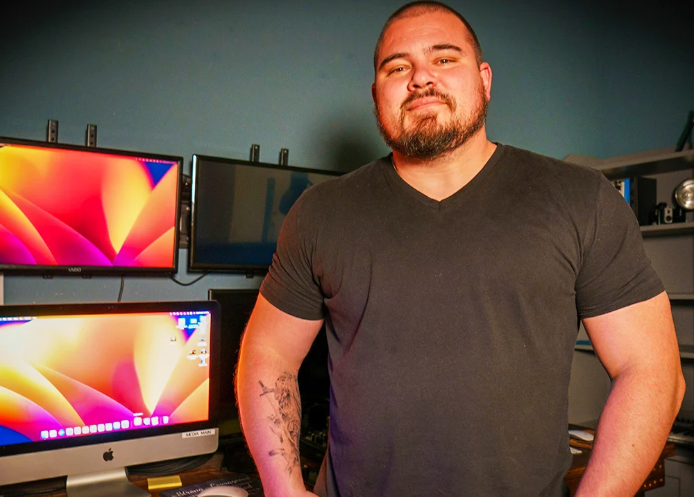Man standing in front of a wall with several computer monitors on it