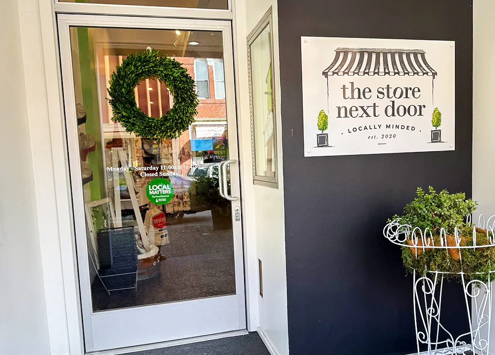 A store's main entrance with a sign that says The Store Next Door