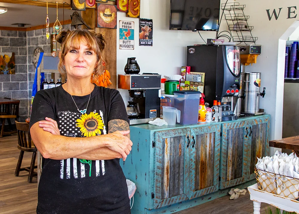 Woman standing in a business smiling with her arms crossed