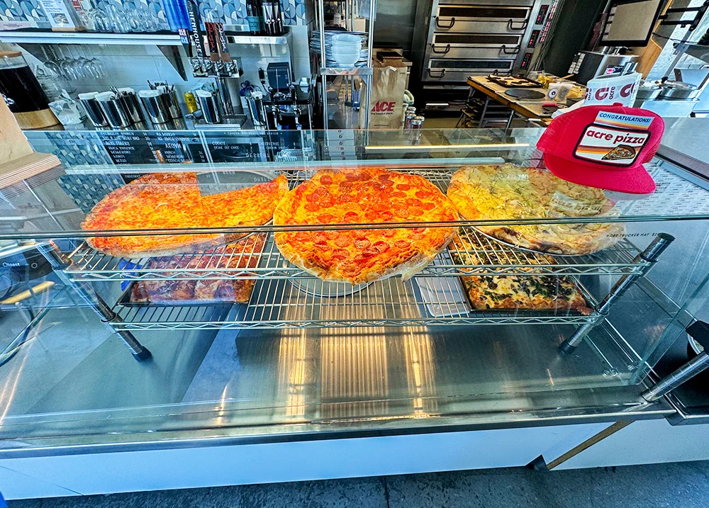 Pizzas on a shelf behind a glass display case