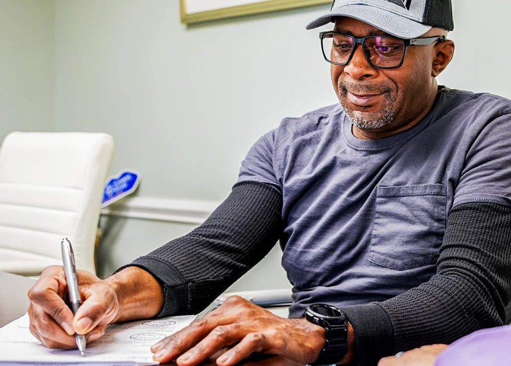 Man sitting at a desk writing on a piece of paper