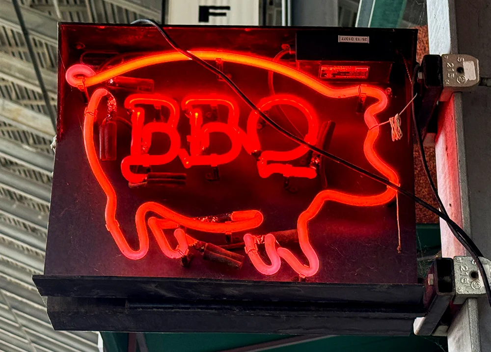 Neon sign in the shape of a pig with BBQ in the middle