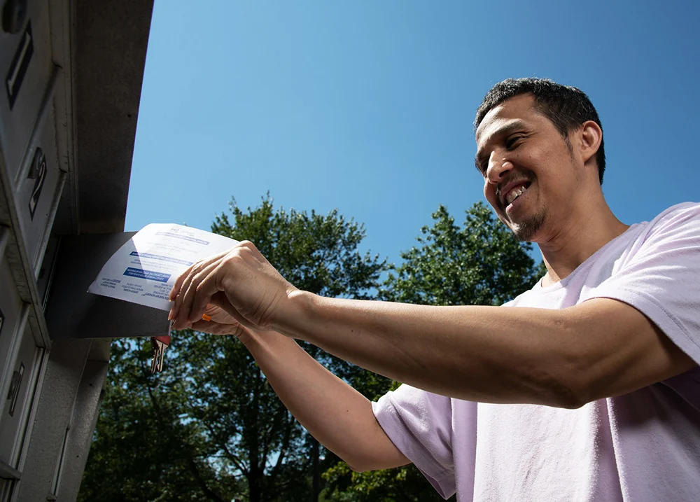 Man putting a piece of mail in a mailbox
