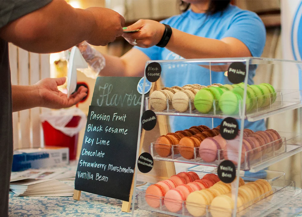 Person selling macrons handing something to a customer