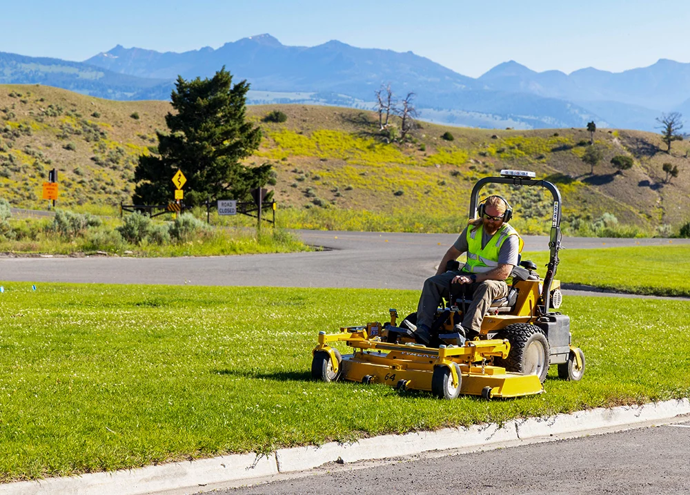 Person mows a lawn on a riding lawn mower