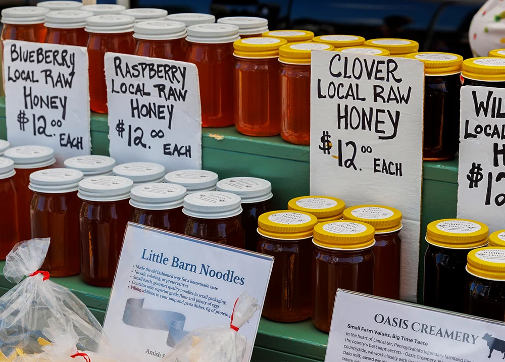 Honey for sale with several signs that say $12