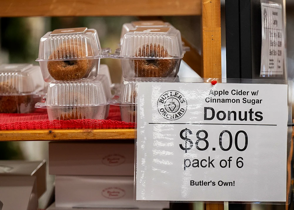 Donuts in plastic containers with a sign that says Donuts $8.00 for Pack of 6