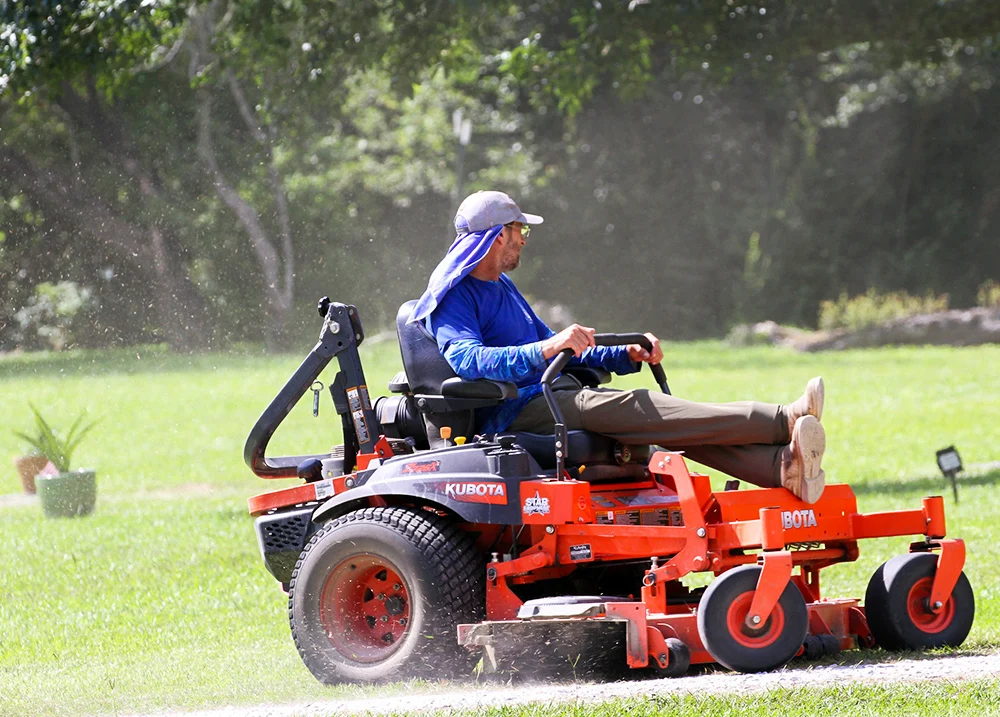 Person mowing a lawn using a riding lawn mower
