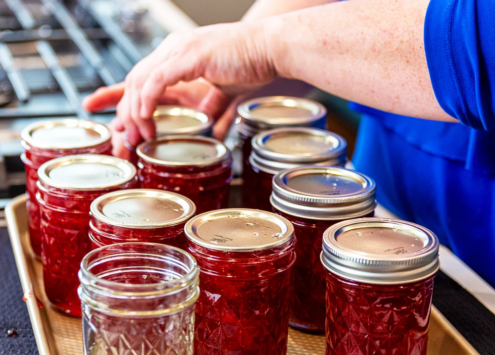 Hands putting lids on jars of jam