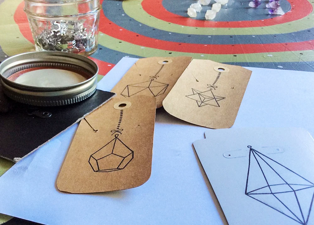 Earring display cards with crystals on the table in the background