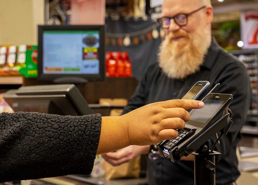 Person paying at the grocery store by scanning their phone over the payment terminal