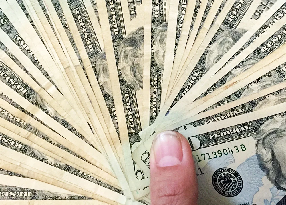 A hand holding a fan of cash