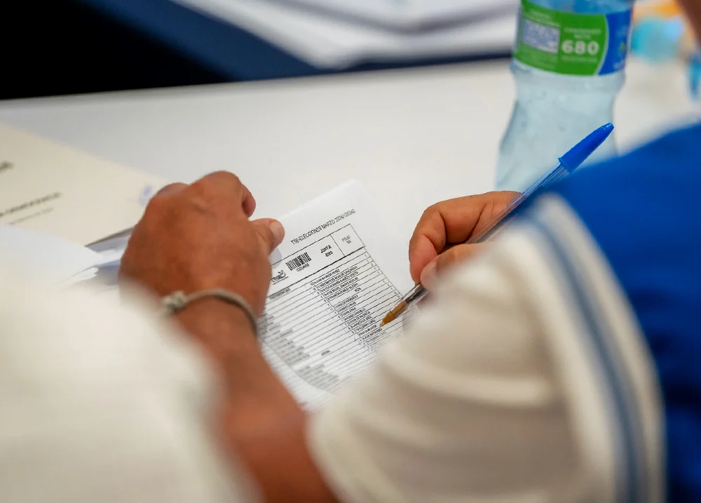Person holding a pen checking items on a spreadsheet