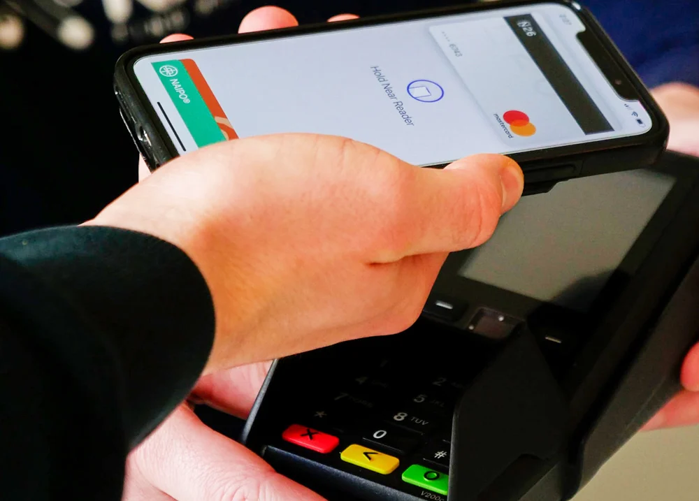 Person scanning their phone at a payment terminal to make a purchase
