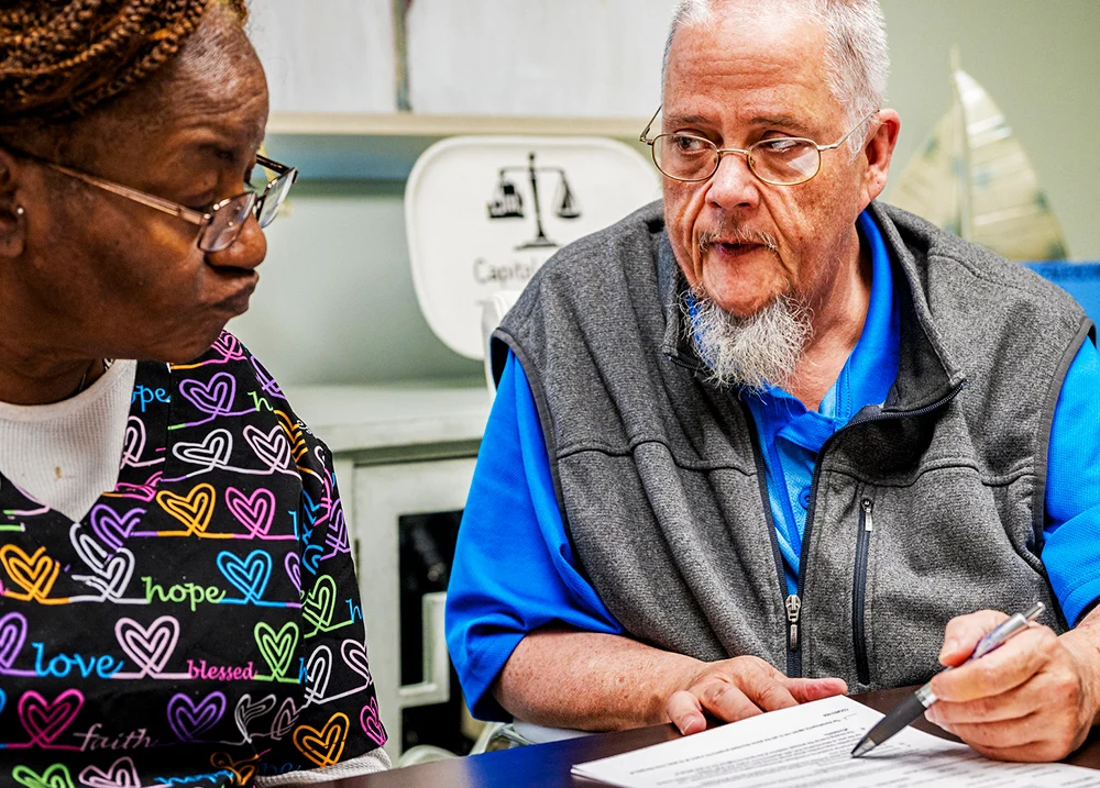 Two people sitting together reviewing a paper on the table between them