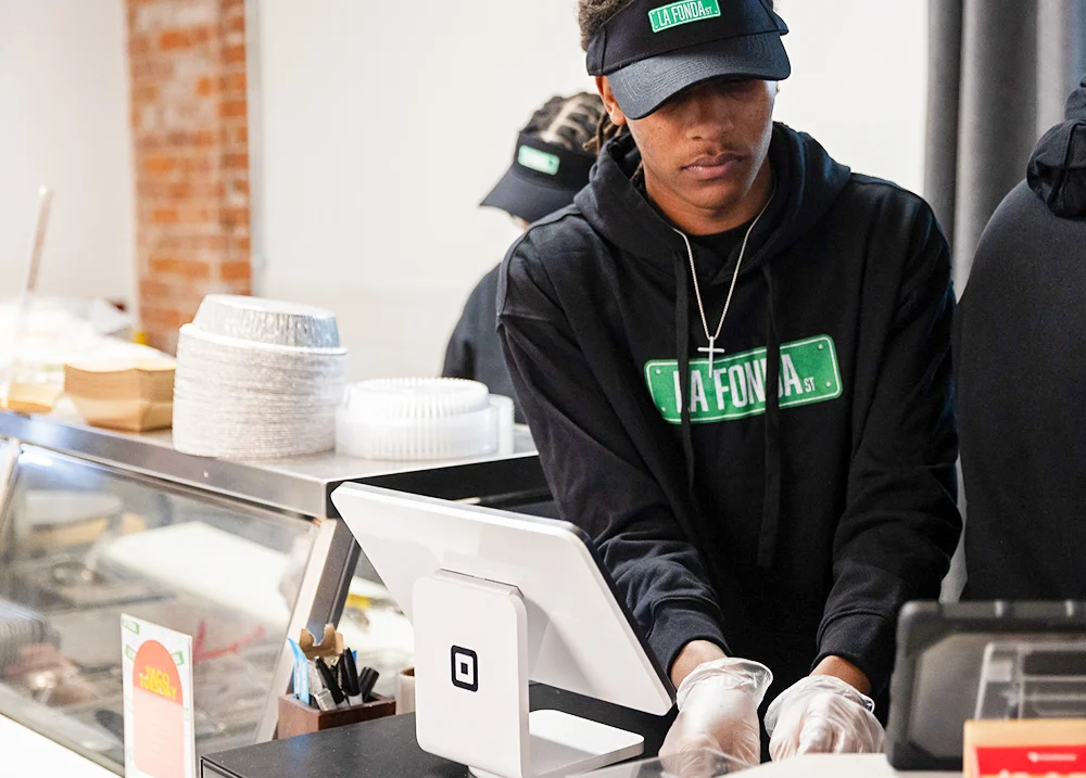Man working at a restaurant with a Square payment terminal in front of him