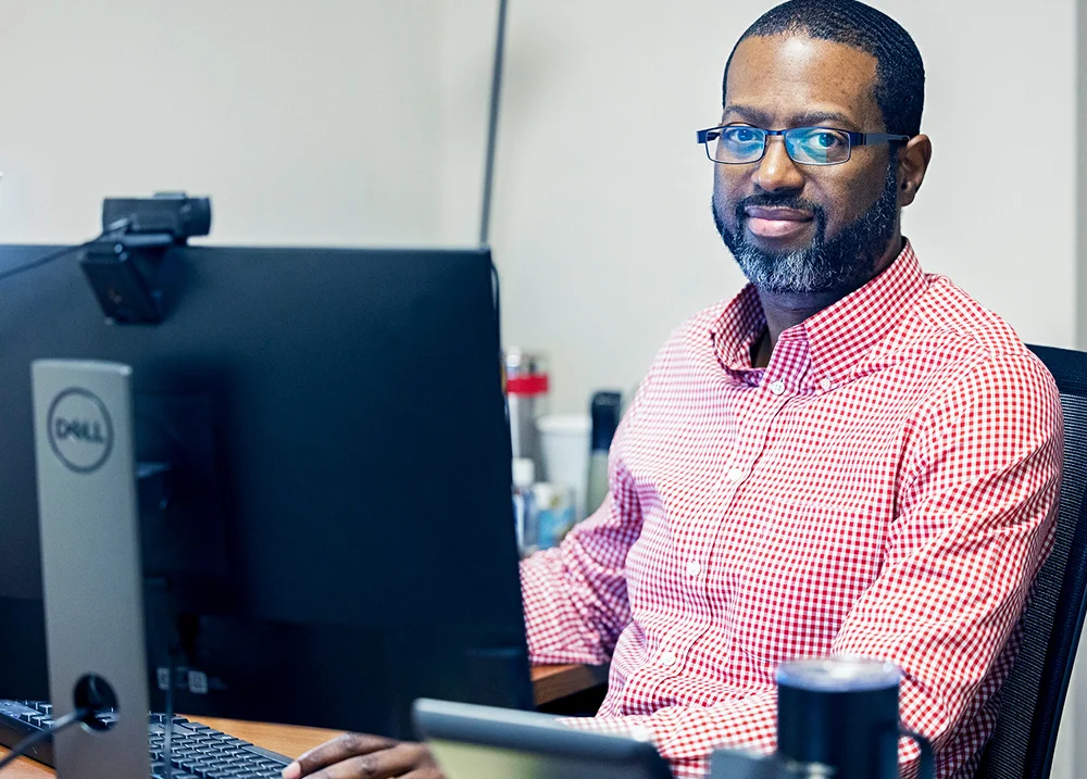 Man sitting behind a computer smiles at the camera