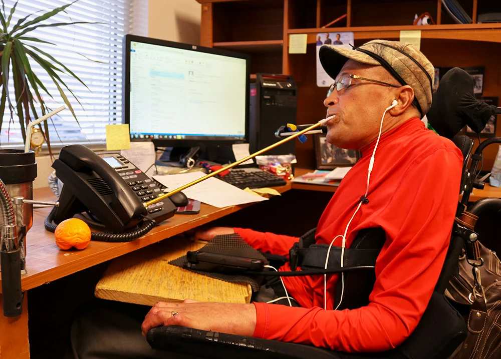 Man who uses a wheelchair dials a phone call with a mouth stick
