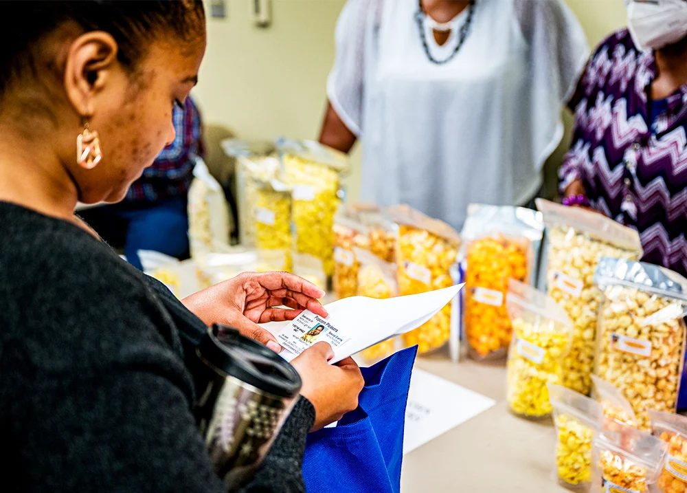 Woman looking at a business card with a popcorn vendor in the background