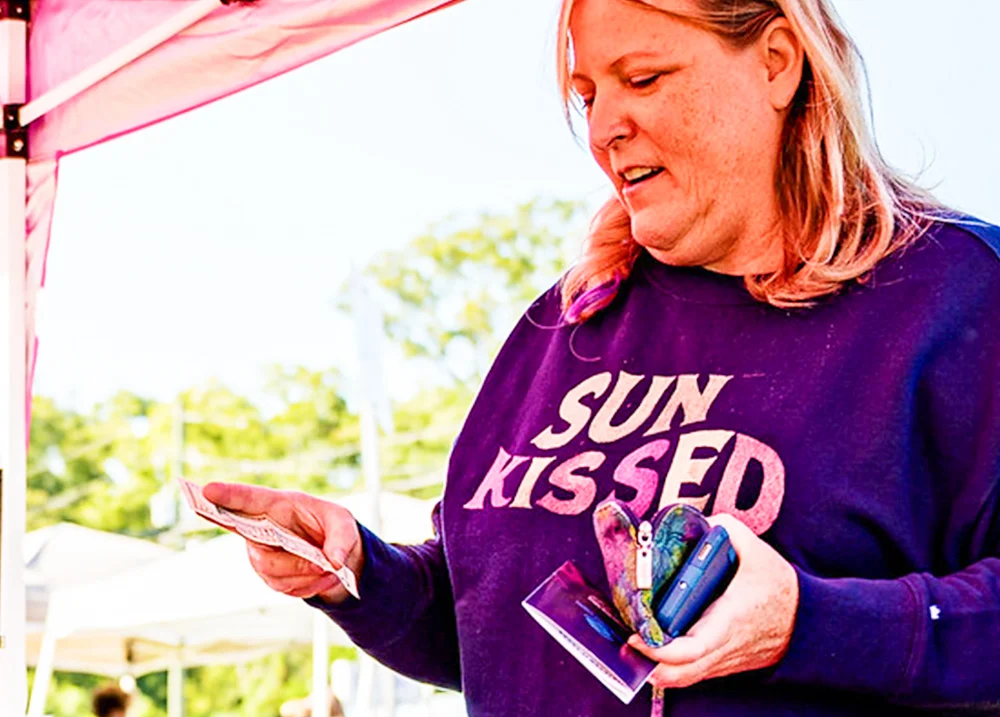 Woman at an outdoor market pulling money out of her wallet